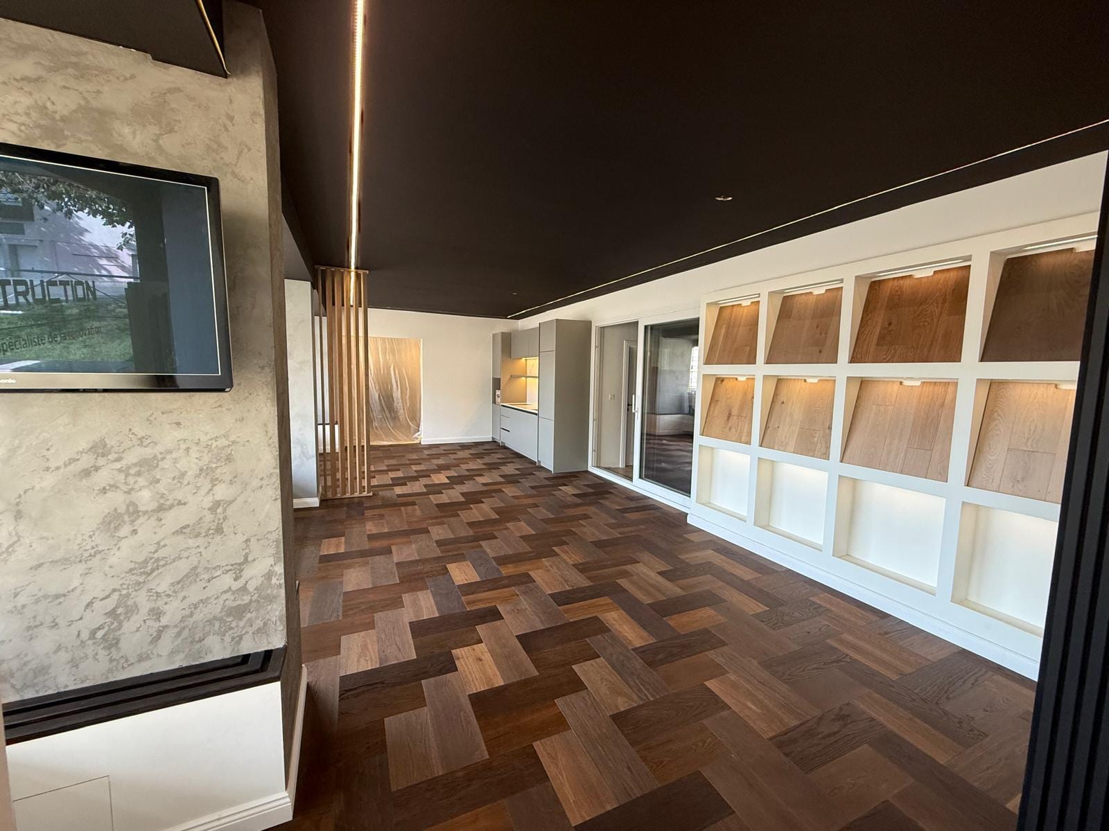 Showroom SP Construction : parquet chêne en bâtons, teintes mélangées, et vitrine d'échantillons